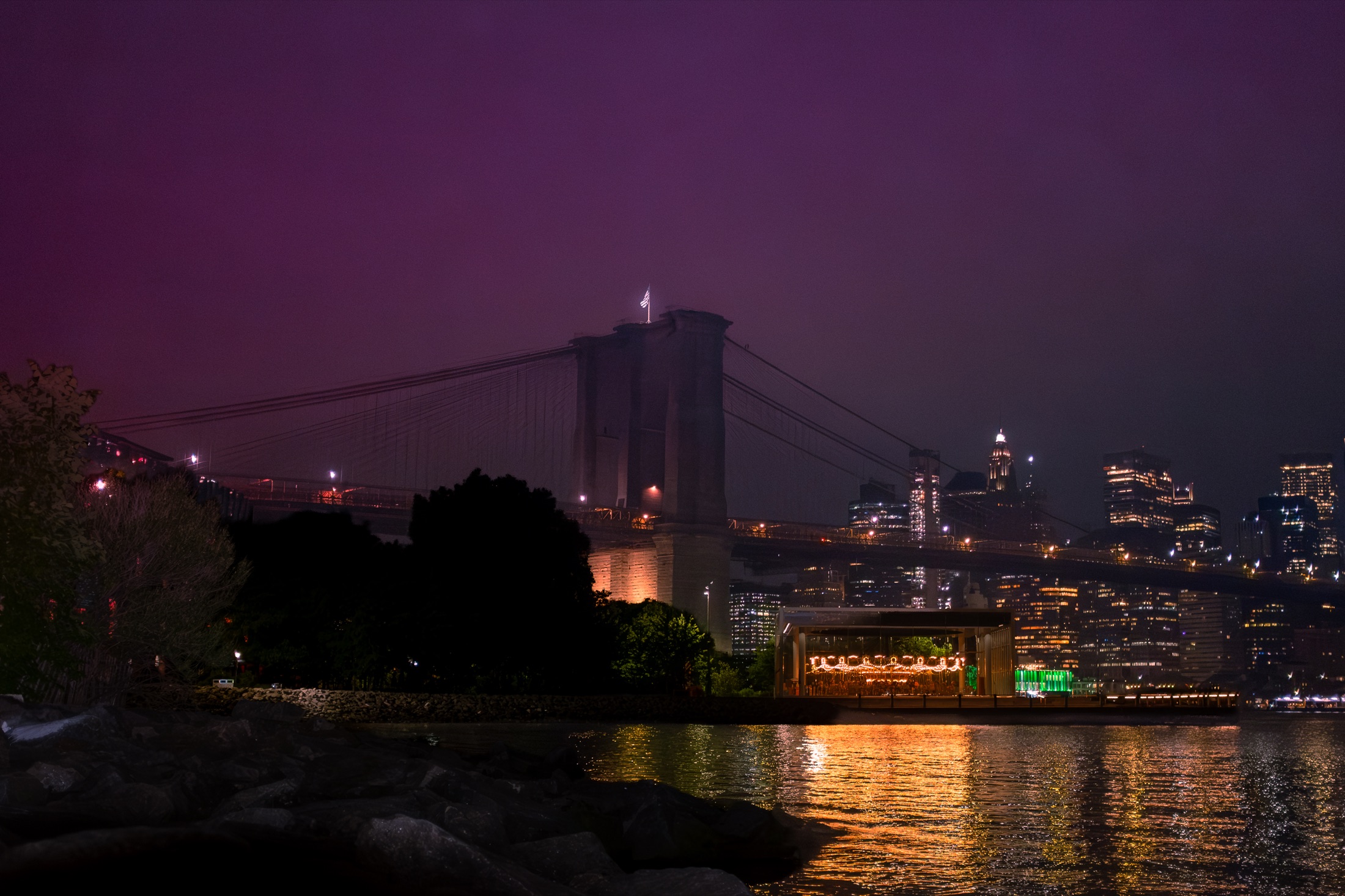 Brooklyn Bridge, skyline, and carousel reflected in the East River