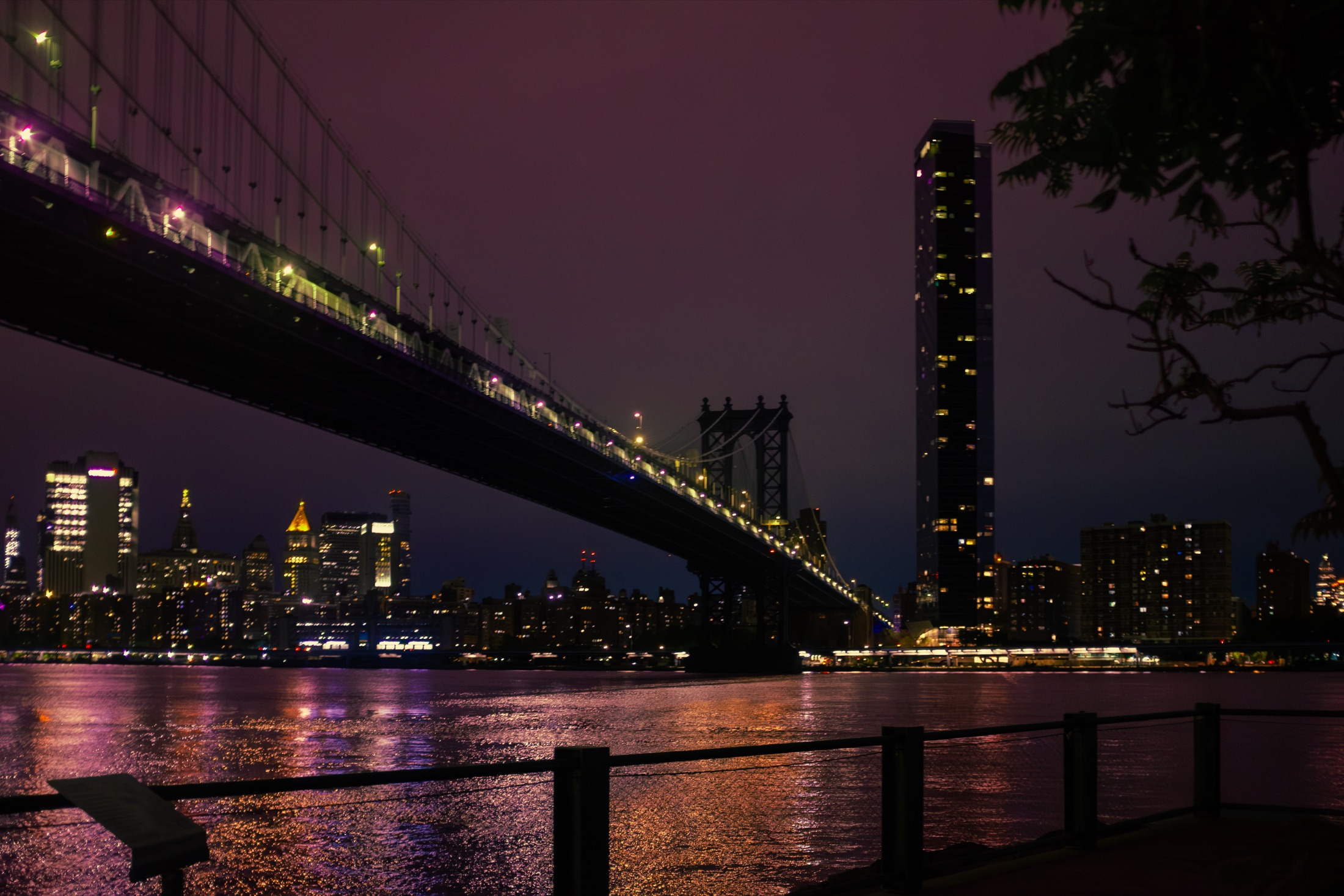Manhattan Bridge and city lights reflected across the East River
